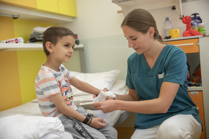 Krankenschwester verbindet Junge die Hand.