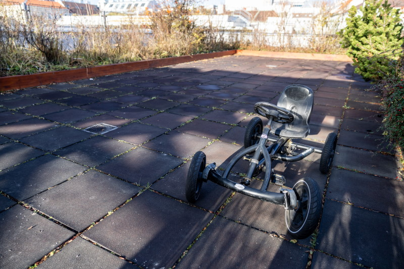 Ein verwaistes Trett-Gokart steht auf auf grauen Bodenplatten.