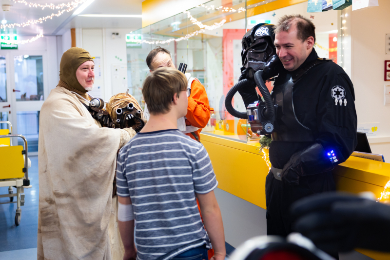 Darth Vader ohne Maske spricht mit Kind.