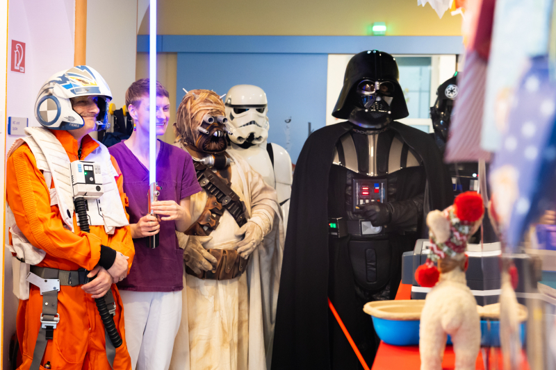 In Star Wars Kostümen verkleidete Menschen im Krankenhaus. Eine Person hält Laserstab.
