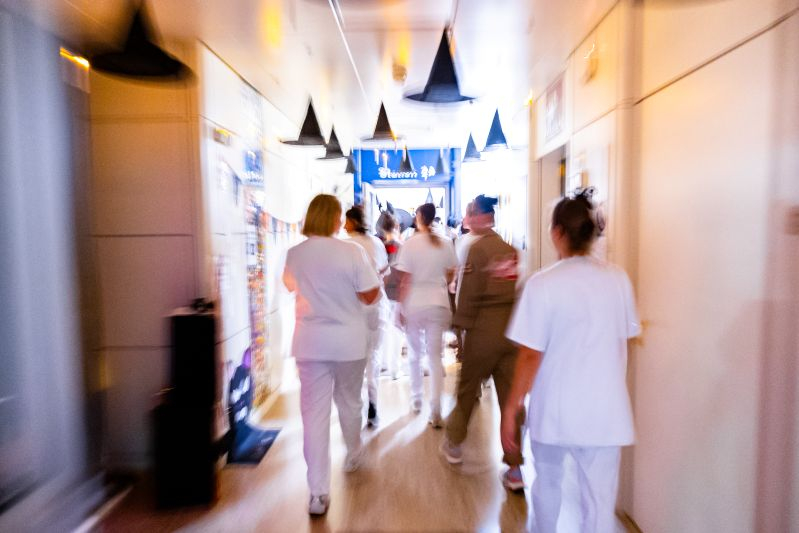 Kinderspital-Personal geht über einen mit Hexenhüten und Kerzen geschmückten Gang.