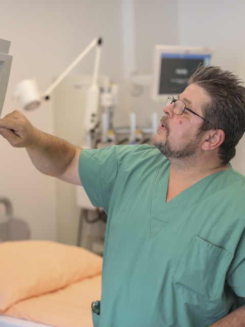 Krankenpfleger zeigt Krankenpflegerin etwas auf einem Monitor.